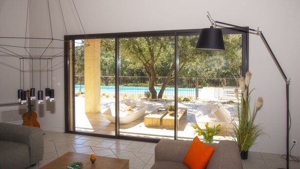 Una sala de estar moderna con un amplio ventanal corredizo que da a una zona de piscina.