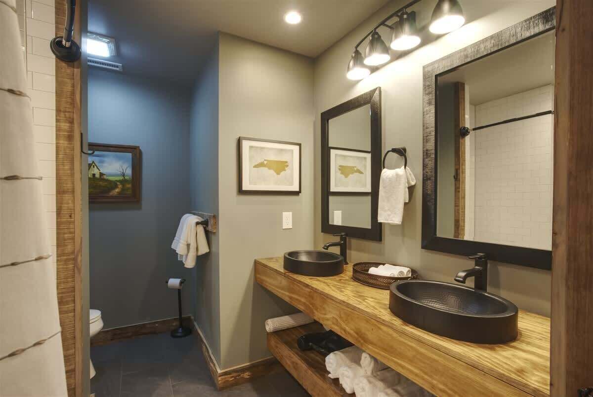A bathroom with a wooden vanity, two sinks, a large mirror, and a towel rack.