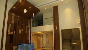 Een ruime lobby met een receptiebalie, een comfortabele zithoek en een trap naar een hoger gelegen verdieping.
