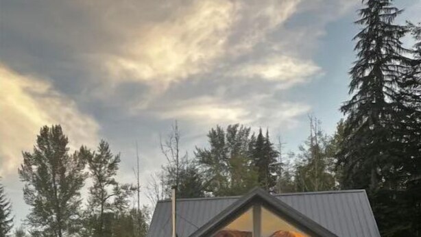 A modern house with a large porch and a triangular roof, surrounded by a grassy yard and tall trees. - Ashford cabin,Mt. Rainier view. Private river access, 17 acres, 5 mi to MRNP (Ashford)