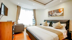 Ein modernes Schlafzimmer mit einem großen Bett, einem Schreibtisch, einem Stuhl und einem Fernseher.