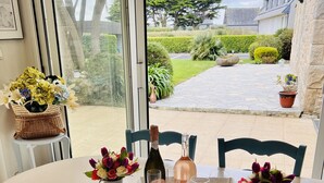 Ein Esszimmer mit Tisch, Stühlen, einer Weinflasche und Blumen in einer Vase.