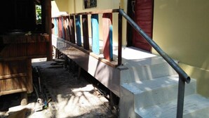Eine Treppe führt zu einem gelben Gebäude, links daneben eine Holzkonstruktion.