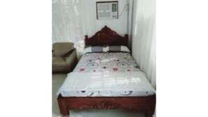 Une chambre avec un lit simple, une chaise et un climatiseur fixé au mur.