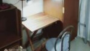 Une petite pièce, de taille modeste, comprenant un lit superposé, un bureau avec une lampe et une chaise.