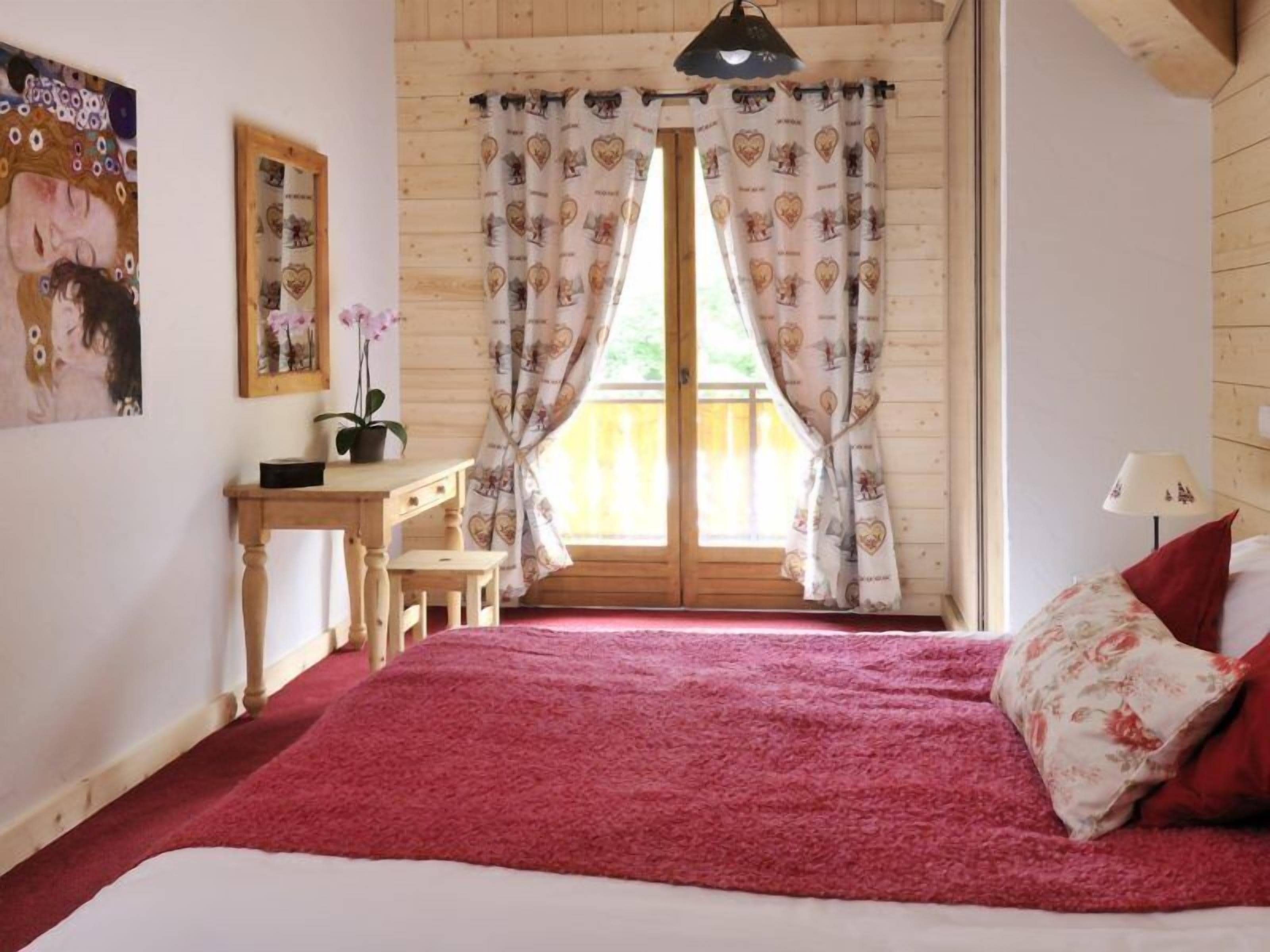Ein gemütliches Zimmer mit einem Bett, einem Schreibtisch und einem fenster mit Vorh ängen.