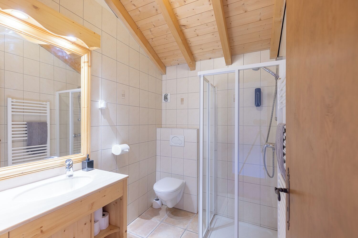 A bathroom with a wooden vanity, a large mirror, a toilet, and a glass shower enclosure.