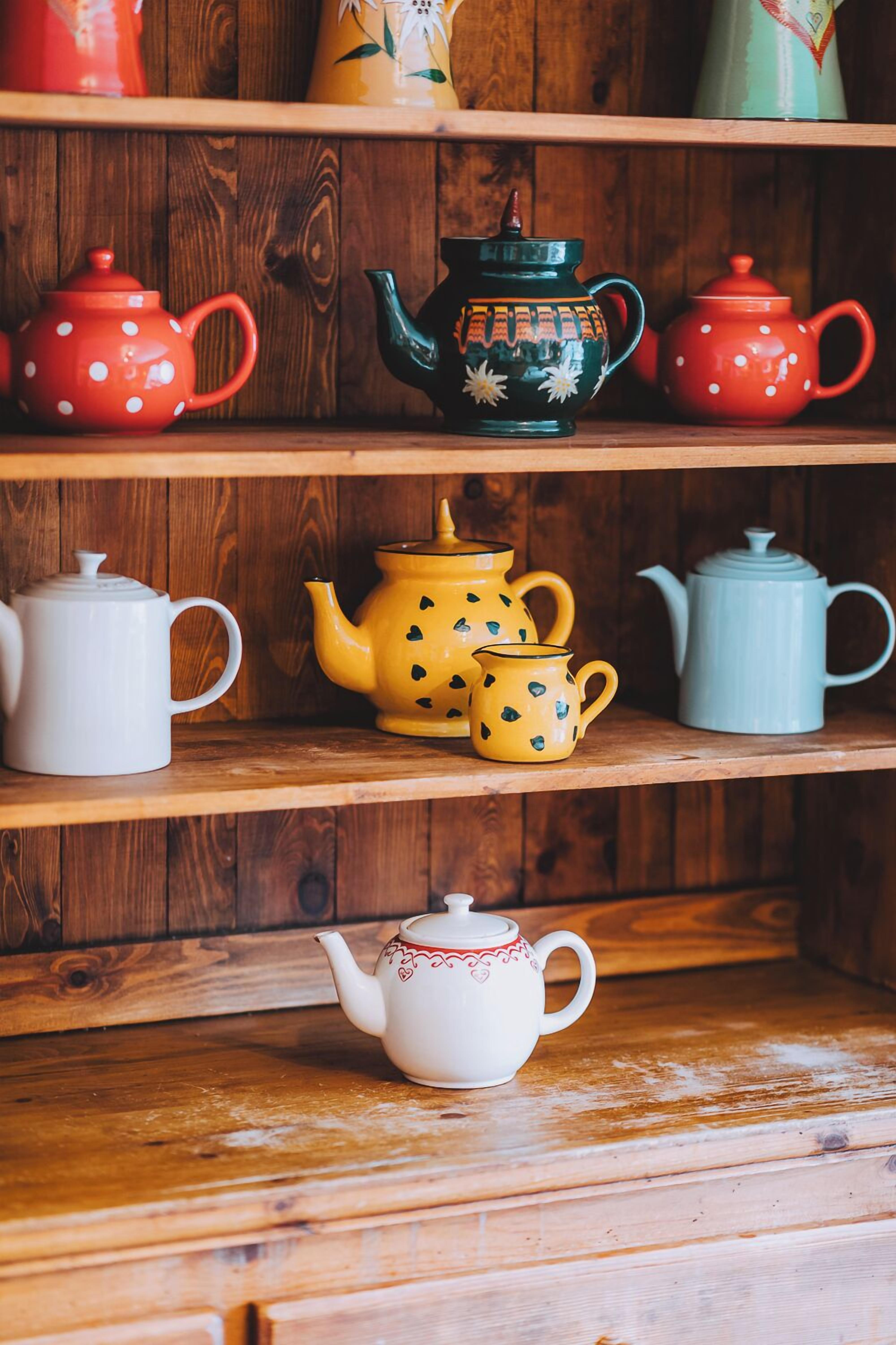 A wooden shelf with various teapots and cups.