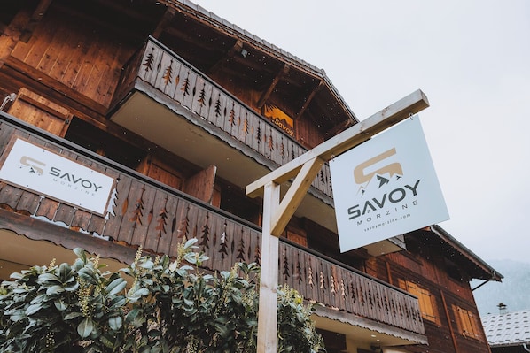 A wooden building with balconies and signs for 'Savoy Morzine'. - Savoy Morzine (Morzine)