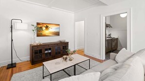 A modern living room with a sofa, coffee table, and a painting on the wall. - The Adaline #1 -  Luxury Hyde Park Apt Near Bayshore (Tampa)