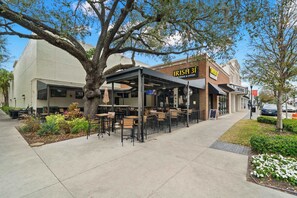 Ett utomhusområde med bord och stolar, en täckt uteplats och en byggnad med en skylt som visar texten "IRISH HOUSE & EATERY".