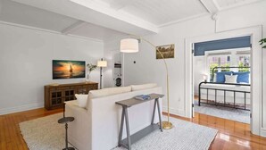 Un salon avec un canapé blanc, une petite table, un lampadaire et un tableau accroché au mur.