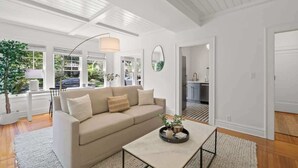 Una sala de estar moderna con un sofá color beige, una mesa de centro con adornos y un ventanal con vistas al exterior.