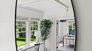 A modern interior with a wooden floor, white walls, and a large window.