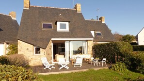 A two-story house with a sloped roof, a patio with outdoor furniture, and a garden area. - House near Presses beach in Saint Philibert (Saint-Philibert)