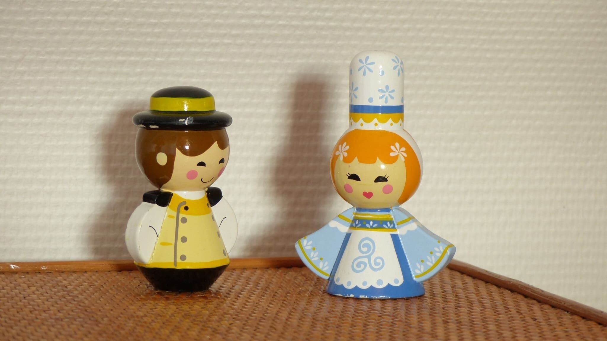 Due piccole statuine in ceramica su una superficie tessuta.