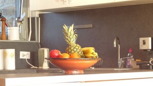 A kitchen counter with a bowl of fruit including a pineapple, oranges, and bananas. - House near Presses beach in Saint Philibert (Saint-Philibert)