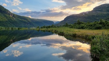 Un lago tranquilo rodeado de ondulantes colinas verdes y un cielo despejado.