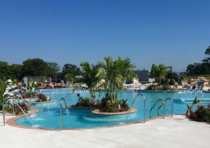 Ein Pool mit kreisförmigem Design, umgeben von Palmen und Liegestühlen.