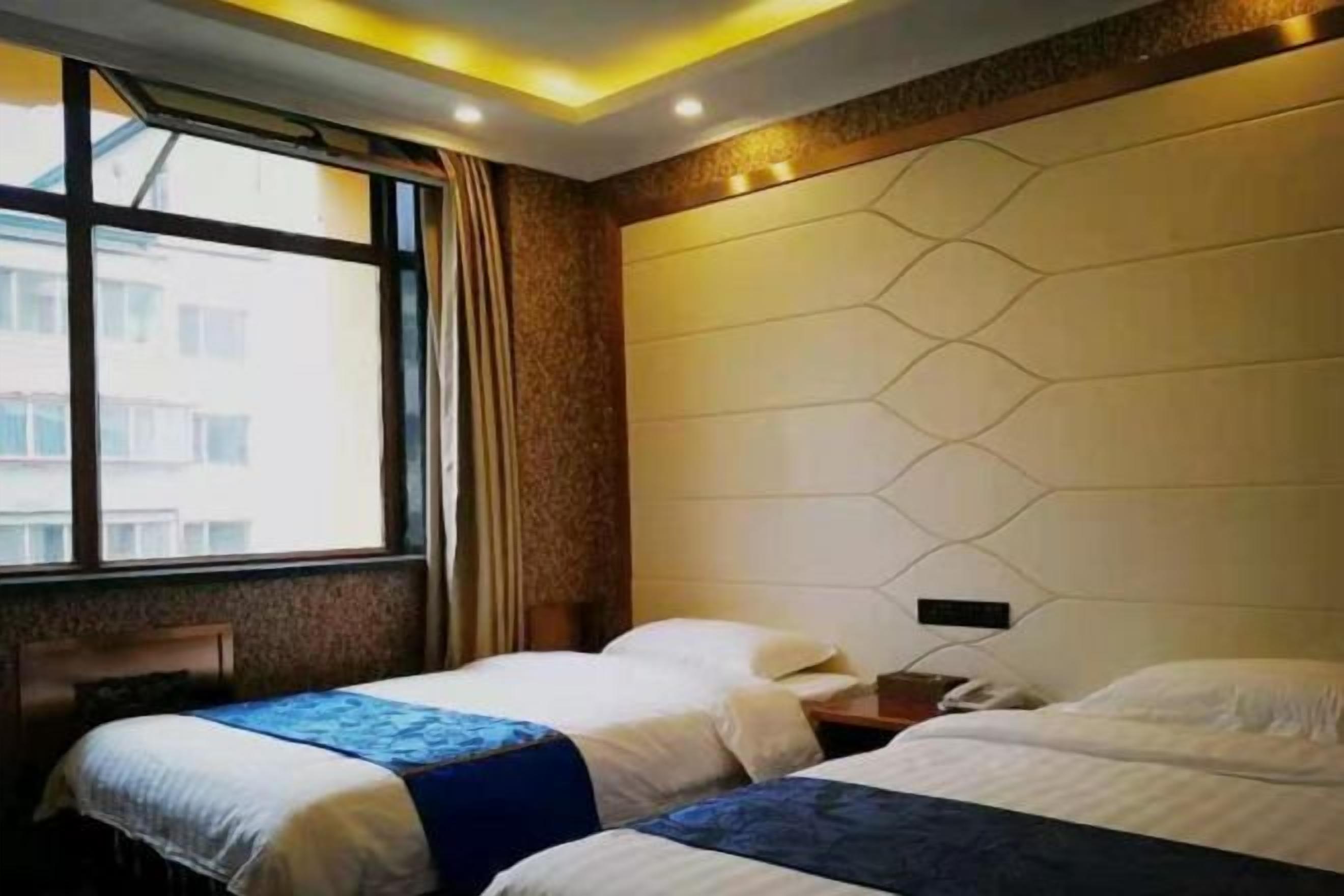 A hotel room with two beds, a window, and a modern wall design.