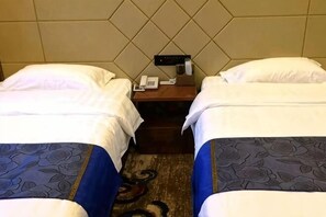 Habitación de hotel con dos camas, una mesita de noche con teléfono y una alfombra estampada.