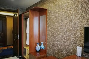 Ein Hotelzimmer mit einem Holzschrank, einer Wand mit Muster und einem kleinen Tisch mit zwei Vasen.
