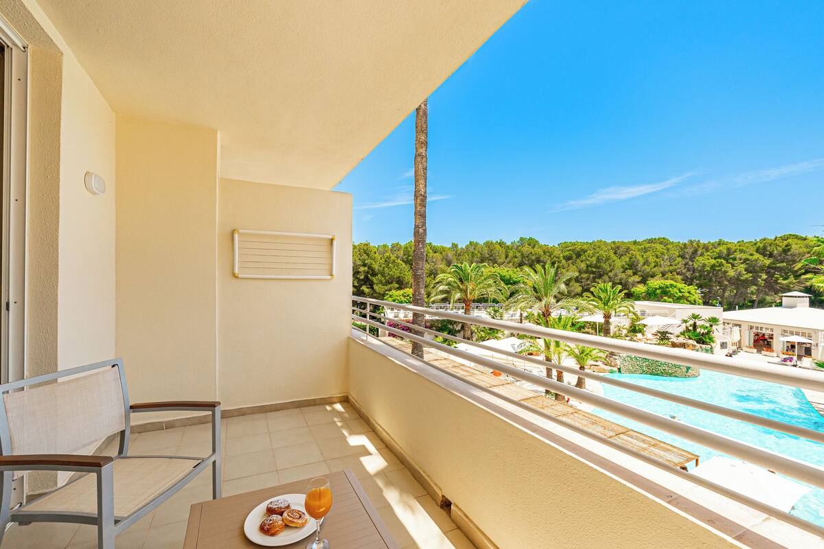 Ein Balkon mit Tisch, Stuhl und Speisen und Getränken.