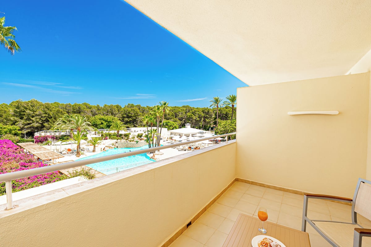Ein Balkon mit Blick auf einen Pool, ein Glas Orangensaft und ein Stuhl.