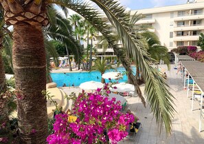 A pool area with palm trees and a building in the background. - Intelier Rosella Hotel by Intelier Hotels & Suites (Sant Llorenc des Cardassar)