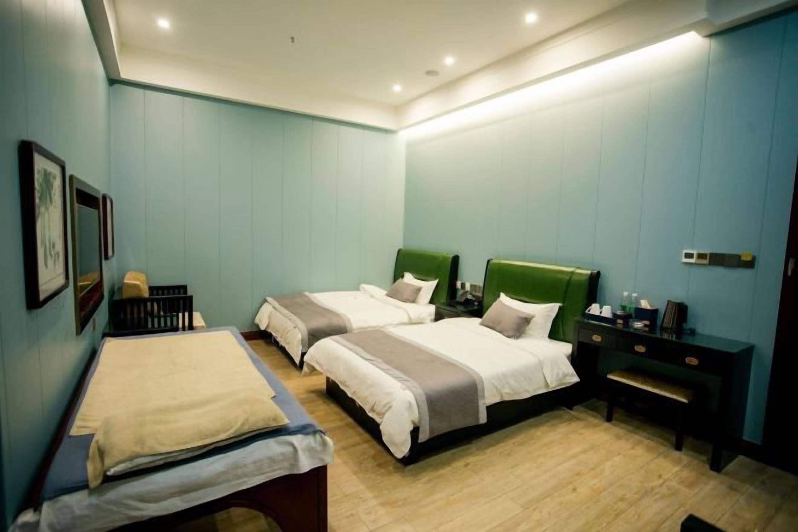 A hotel room with two beds, a desk, and a bench.