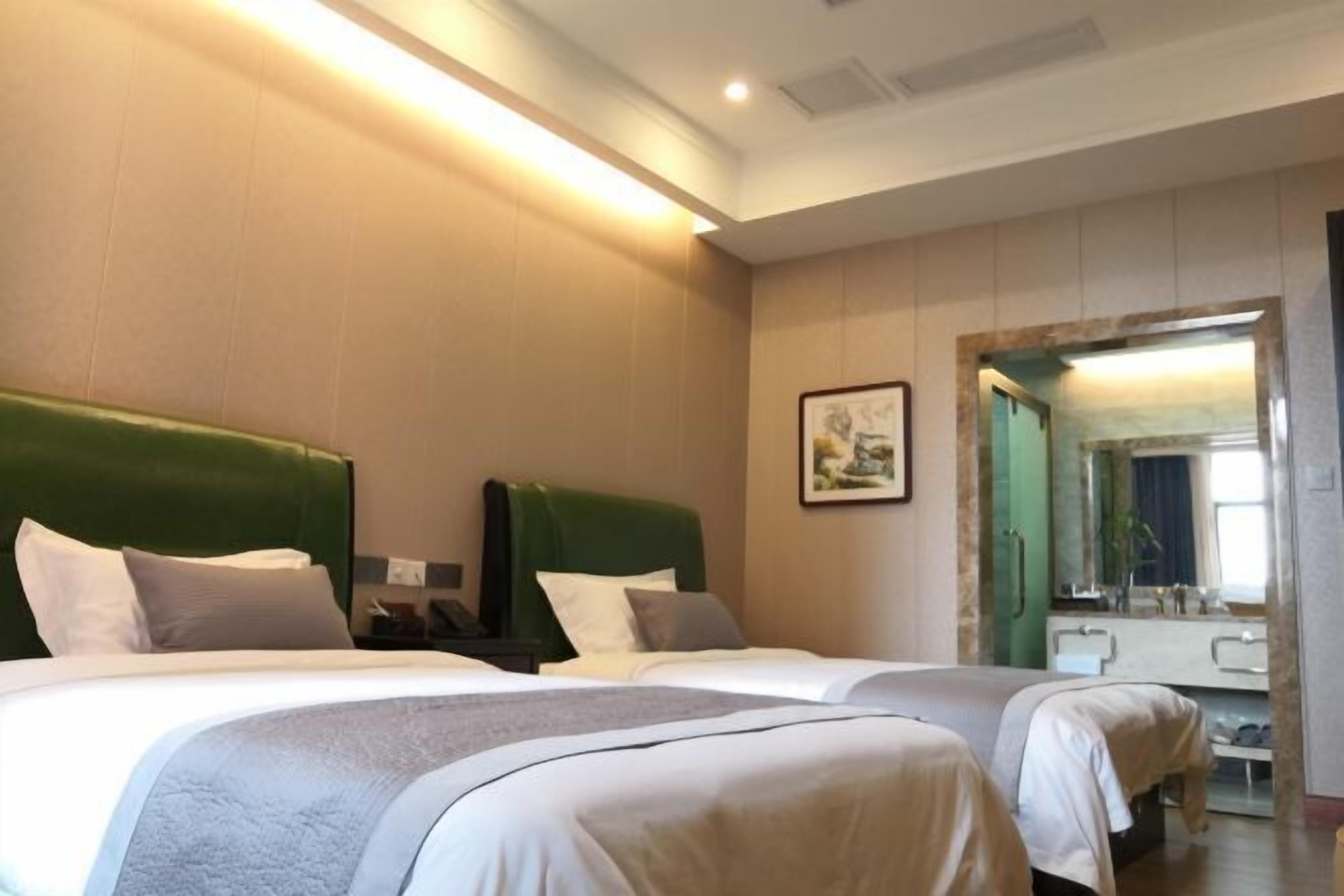 A hotel room with two beds, a large mirror, and a framed picture on the wall.