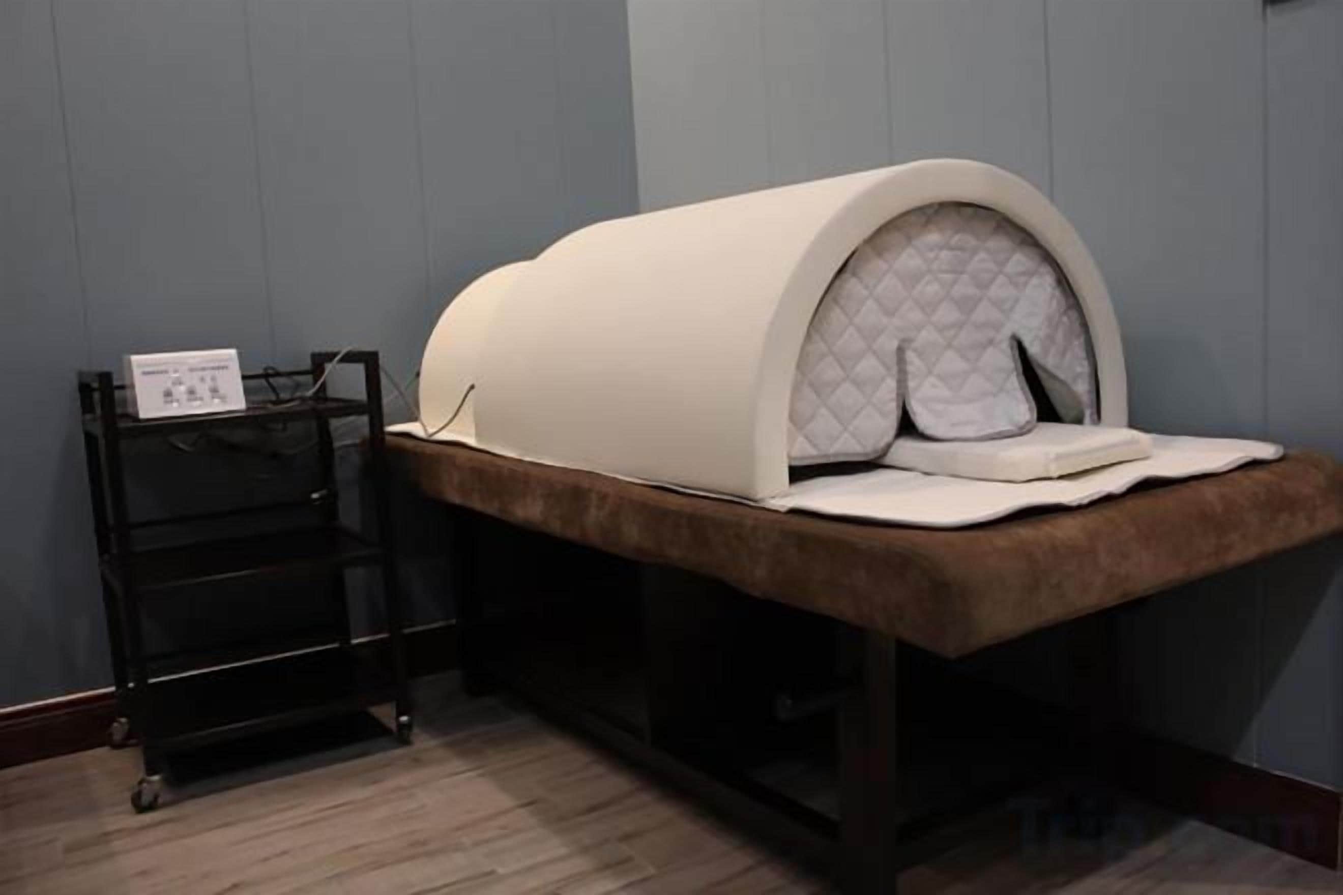 A room with a bed, a small table, and a wall-mounted shelf.