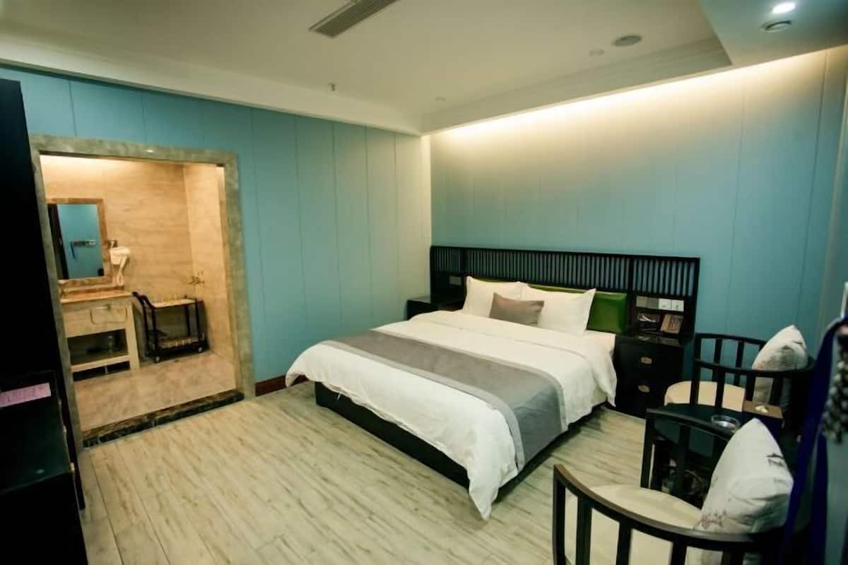 Un dormitorio moderno con cama, mesita de noche, silla y un escritorio pequeño.