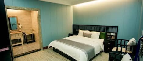 A modern bedroom with a bed, bedside table, chair, and a small desk.