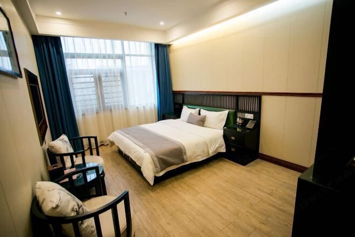 Habitación de hotel con una cama grande, un escritorio, una silla y una mesita de noche.