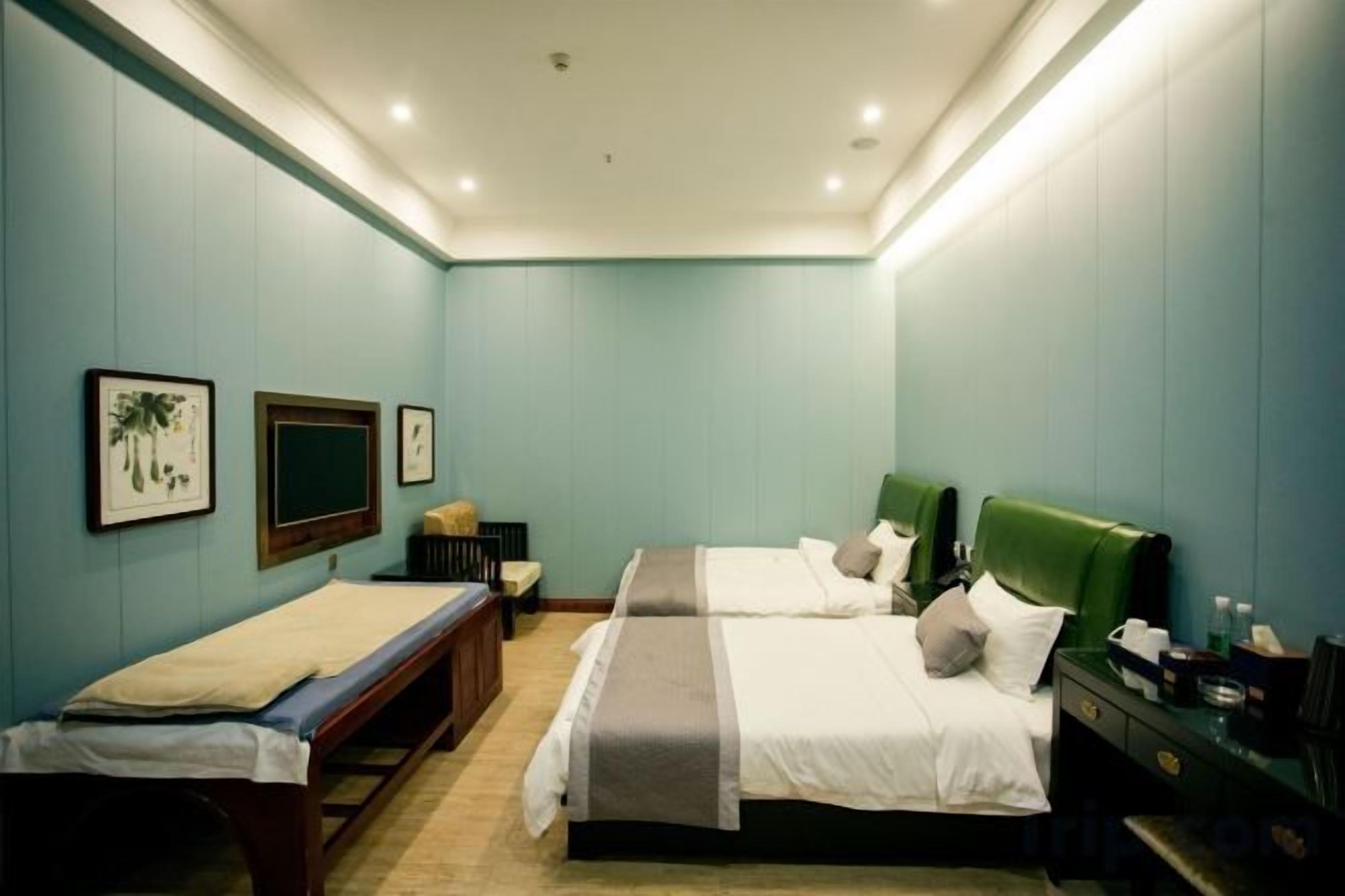 Ein Hotelzimmer mit zwei Betten, einem Schreibtisch, einem Sessel und einem Fernseher.