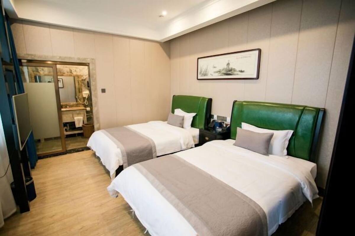 Habitación de hotel con dos camas, un espejo, un escritorio y un cuadro en la pared.