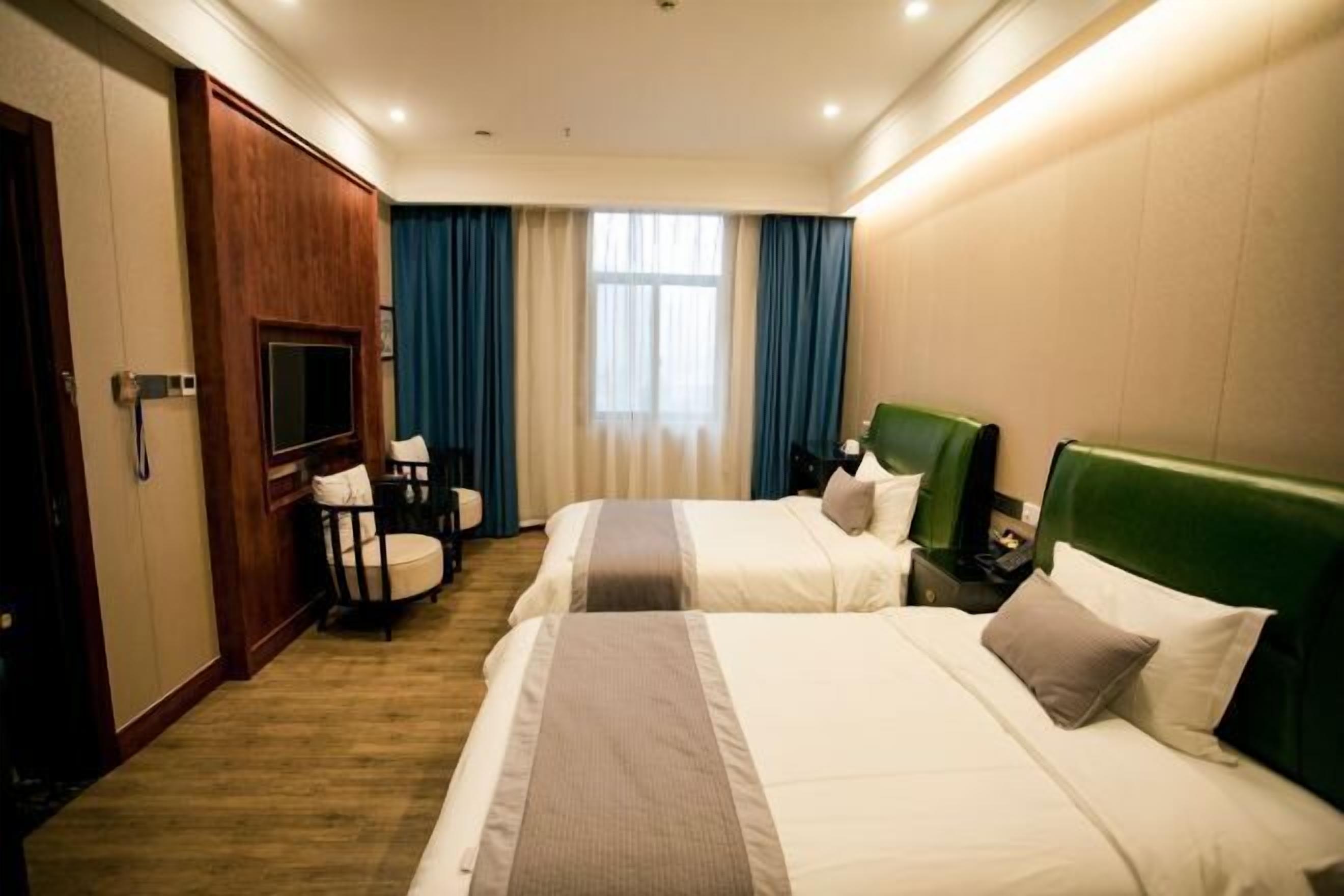 A hotel room with two beds, a television, a desk, and a chair.