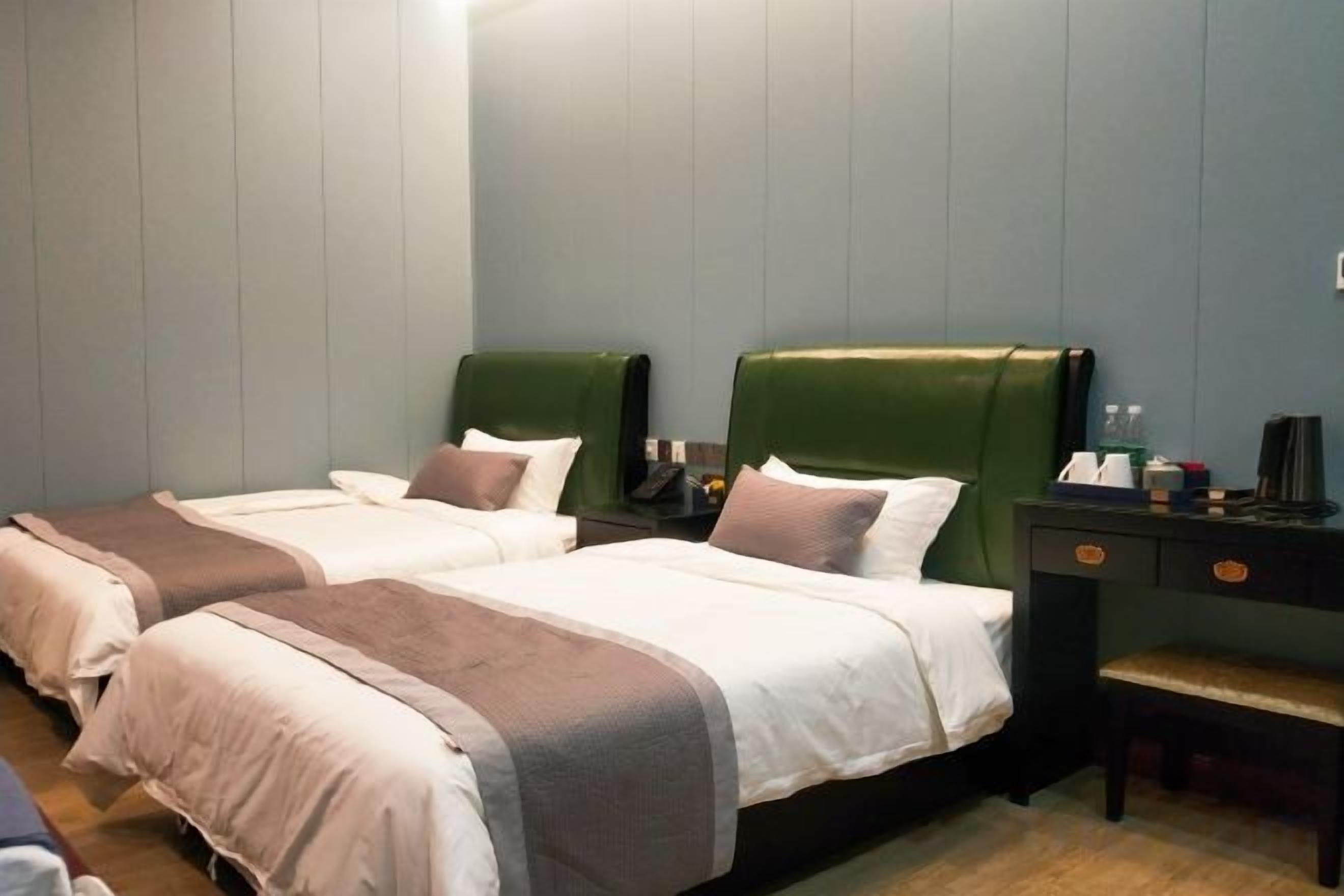 Habitación de hotel con dos camas, un escritorio y un banco.