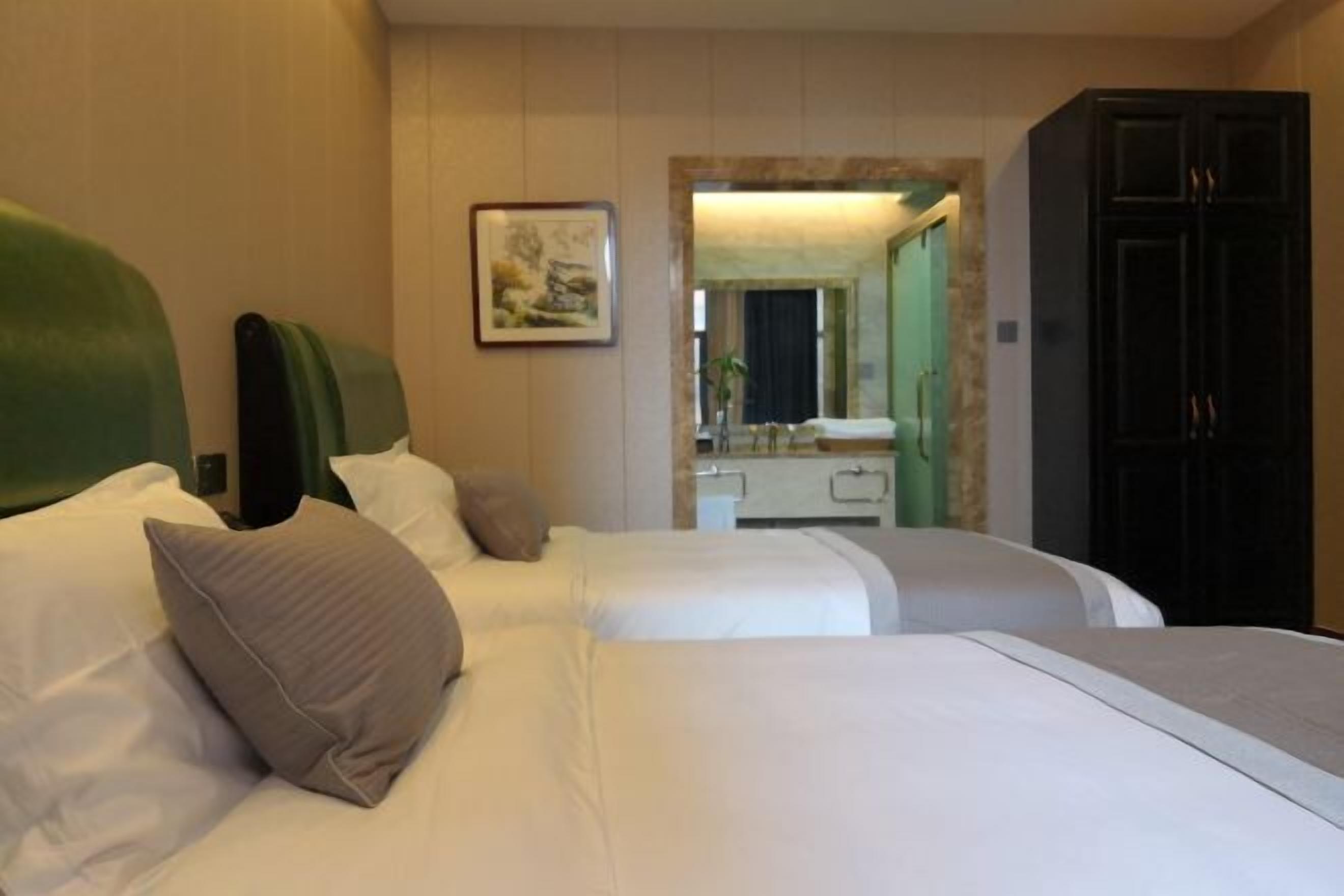 Habitación de hotel con dos camas, un espejo, un tocador y un armario.