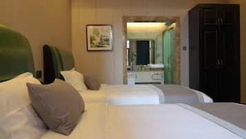 A hotel room with two beds, a mirror, a dresser, and a cabinet.