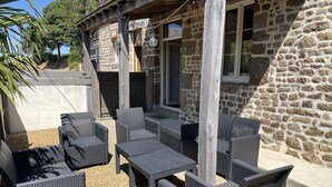 Un espace extérieur aménagé avec des meubles en osier et un bâtiment en pierre en arrière-plan.