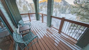 A wooden deck with metal railings, a table, and chairs. - Updated Condo w/Covered Deck & Great Views! (Keystone)