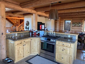 A log cabin kitchen with wooden cabinets, a Bosch stove, granite countertops, and a hanging light fixture. - Gorgeous Log Cabin estate with hot tub, views, privacy and sauna ! (Durango)