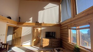 A log cabin interior with a cozy living area, a television, and a view of the outdoors. - Gorgeous Log Cabin estate with hot tub, views, privacy and sauna ! (Durango)