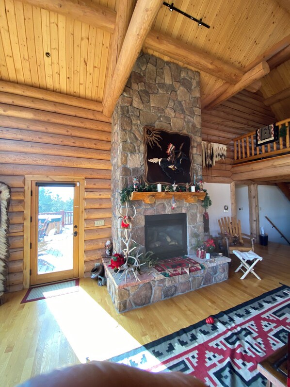 A log cabin interior with a stone fireplace, wooden ceiling beams, and a rustic decor. - Gorgeous Log Cabin estate with hot tub, views, privacy and sauna ! (Durango)