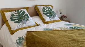 Een slaapkamer met een bed, een ronde spiegel en een nachtkastje met een lamp.