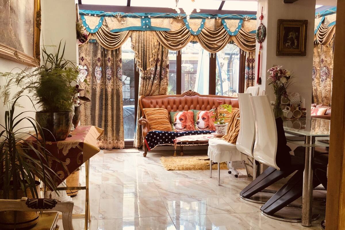 Una sala de estar amplia con un sofá grande, una mesa de comedor y una araña.