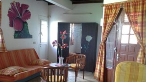 Ein Wohnzimmer mit einer Couch, zwei Sesseln, einem kleinen Tisch und einer Tür mit floralen Verzierungen.