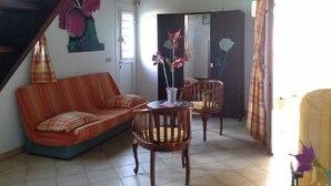 Ein Wohnzimmer mit einer Couch, zwei Holzstühlen, einem Tisch mit einer Vase und einer Treppe mit floralem Wandbild.